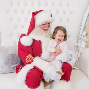 Little girl posing with Santa in professional holiday photo shoot