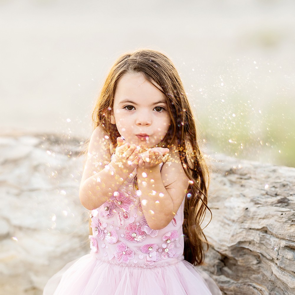 Beach Photography Watch Hill, Napatree Point, Westerly, RI - girl blowing glitter at camera with rocks behind her