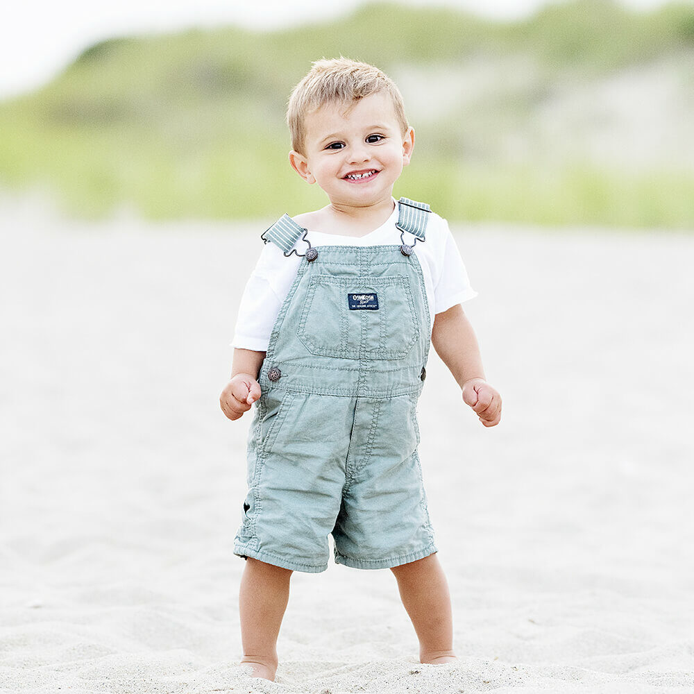 Beach Photography Rhode Island Family Photography of boy standing on beach in overalls.